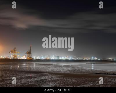 Redcar, Redcar et Cleveland, Redcar et Cleveland, 2022. Vue générale vers le sud-ouest à travers l'embouchure de l'estuaire de la rivière Tees au crépuscule depuis South Gare, avec les zones industrielles illuminées de Teesport et Seal Sands en arrière-plan. Banque D'Images