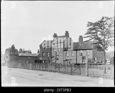 Boyce's Cottages, Garratt Lane, Earlsfield, Wandsworth, Greater London Authority, 1880-1900. L'extérieur des Boyce's Cottages sur Garratt Lane. Cette rangée de chalets a pris son nom du propriétaire, Mr A E Boyce. Lorsque cette photographie a été prise, probablement vers la fin du XIXe siècle, deux des chalets portent des enseignes annonçant l'entreprise de déménagement de John Newbon. À cette époque, la famille Newbon occupa un certain nombre de maisons de Boyce's Row. Au début du XXe siècle, l'entreprise s'était déplacée sur une courte distance le long de Garratt Lane et en 1916 Boyce's Row avait été démolie. Sheringham court appartements no Banque D'Images