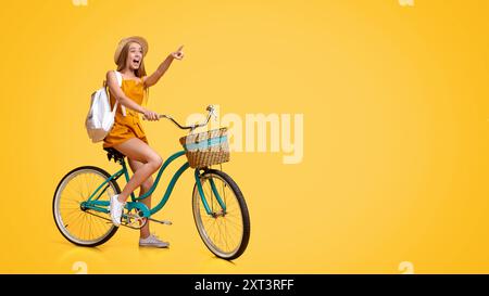 Soldes d'été. Excitée Girl Riding Bicycle et pointant de côté à l'espace de copie Banque D'Images