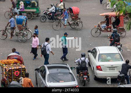 Un officier de la police de la circulation du Bangladesh donne des instructions aux conducteurs après que la police a annulé leur grève et repris leurs fonctions à la suite d'une réunion avec le gouvernement intérimaire. La police bangladaise a repris ses patrouilles dans la capitale Dacca, mettant fin à une grève d'une semaine qui a laissé un vide juridique et de l'ordre après l'éviction brutale de l'ancien premier ministre autocratique Sheikh Hasina. Banque D'Images