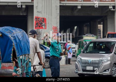 Un officier de la police de la circulation du Bangladesh donne des instructions aux conducteurs après que la police a annulé leur grève et repris leurs fonctions à la suite d'une réunion avec le gouvernement intérimaire. La police bangladaise a repris ses patrouilles dans la capitale Dacca, mettant fin à une grève d'une semaine qui a laissé un vide juridique et de l'ordre après l'éviction brutale de l'ancien premier ministre autocratique Sheikh Hasina. Banque D'Images