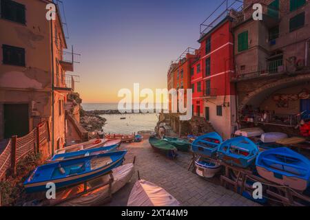 Village de Riomaggiore, bateaux en face de la mer au coucher du soleil. Parc national des Cinque Terre, région Ligurie, Italie, Europe. Banque D'Images