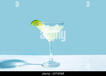 Margarita ou Daiquiri cocktail en verre avec citron vert sur fond bleu, espace copie. Concept tendance de cocktail party, recette de cocktail classique. Banque D'Images