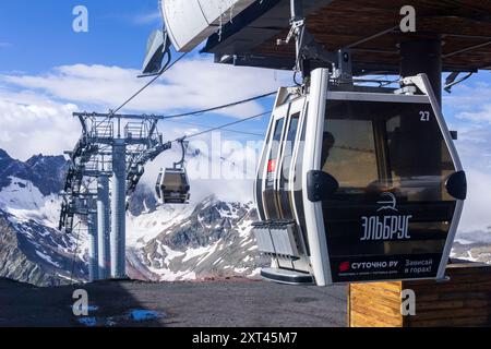 Elbrus, Russie - 31 juillet 2024 : télécabine sur la pente du mont Elbrus avec des montagnes enneigées en arrière-plan Banque D'Images