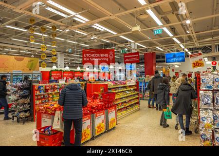 Zone de caisse animée des hypermarchés avec des acheteurs utilisant à la fois les caisses traditionnelles et les caisses en libre-service pour leurs achats. Suède. Banque D'Images