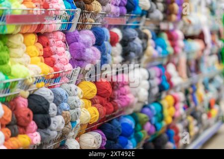 Étagères remplies de boules de fil colorées dans le magasin d'artisanat, textures vibrantes amateurs de tricot, mise au point sélective Banque D'Images