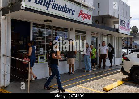 San Juan, États-Unis. 13 août 2024. Les Portoricains font la queue dans une boulangerie pour faire le plein de pain et d'autres aliments avant la tempête tropicale Ernesto à San Juan, Porto Rico, le 13 août 2024. La tempête tropicale Ernesto devrait frapper l'archipel entre mardi soir et mercredi matin. Crédit : Sipa USA/Alamy Live News Banque D'Images