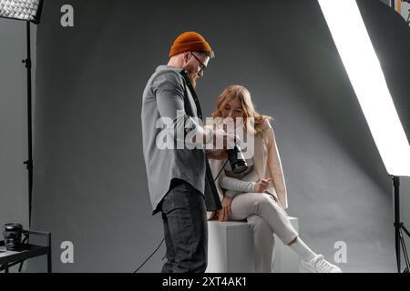 Photographe et mannequin collaborant dans un photoshoot en studio, examinant des clichés pour un projet de mode Banque D'Images