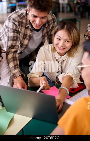 Groupe de jeunes étudiants souriants divers utilisant l'ordinateur portable rassemblement assis dans la salle de classe de l'université. Banque D'Images