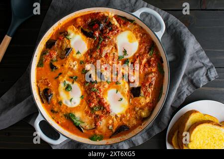 Aubergine Parmigiana Shakshuka dans une grande casserole à braiser : cuisine fusion italienne-moyen-orientale végétarienne servie dans une grande casserole avec un côté d'ail br Banque D'Images