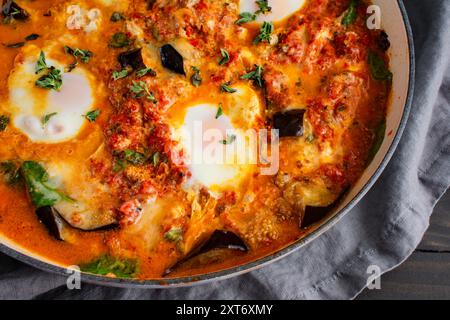 Aubergine Parmigiana Shakshuka dans une grande casserole à braiser : cuisine fusion italienne-moyen-orientale végétarienne servie dans une grande casserole avec un côté d'ail br Banque D'Images