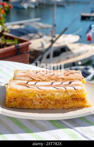 Portion de gâteau français mille feuilles, tranche de vanille ou de crème anglaise, pâte feuilletée Napoléon recouverte de crème pâtissière servie en plein air à Port Grimaud, France Banque D'Images