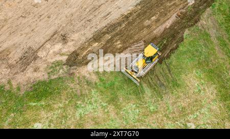 le bulldozer jaune bouge et aplatit le sol. terrassement sur chantier. photo aérienne. Banque D'Images