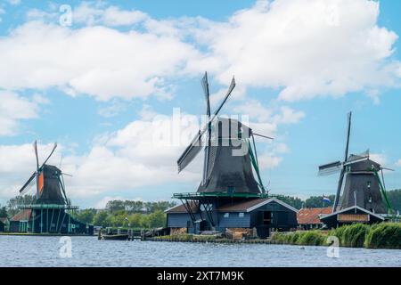 Pays-Bas. Jour nuageux d'été à Zaanse Schans. Trois moulins à vent vintage mais fonctionnels sur la rive d'un canal Banque D'Images