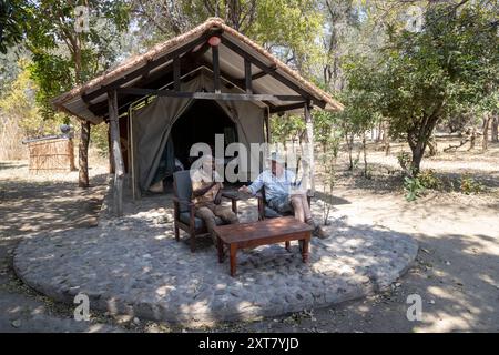 Touriste d'âge moyen assis avec son guide au camp de tentes de la communauté d'Ituba attenant au parc national de North Luangwa, Zambie Banque D'Images