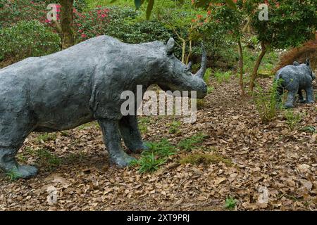 Sculptures de jardin de rhinocéros entourés d'arbres, de fleurs et de feuillage vert, jardins de l'Himalaya, Ripon, ROYAUME-UNI. Banque D'Images