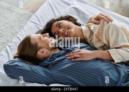 Un couple aimant câlin au lit, partageant un moment tendre. Banque D'Images