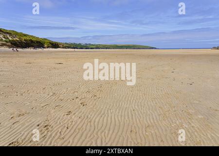 À marée basse, les empreintes dans le sable ondulé de la plage de Crantock mènent vers la mer lointaine. Banque D'Images