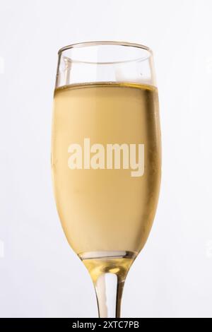 Plan vertical d'un verre à champagne rempli vu de dessous, placé sur un fond blanc. Parfait pour les fêtes de fin d'année et le réveillon du nouvel an. Banque D'Images