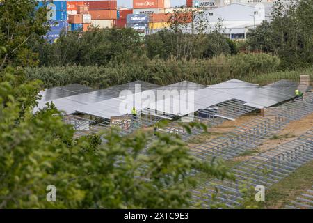 Les ouvriers construisent une grande centrale photovoltaïque près d’une zone industrielle Banque D'Images