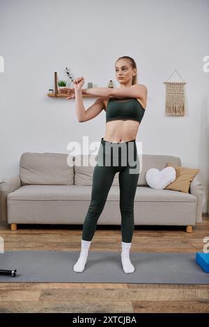 Une jeune femme étire ses bras avant de faire de l’exercice chez elle. Banque D'Images