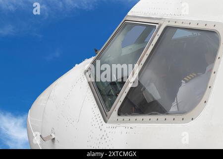 Avion volant. Commandant dans le cockpit vu de l'extérieur à travers la fenêtre de l'avion à réaction commercial. Fuselage et vitres avant. Banque D'Images