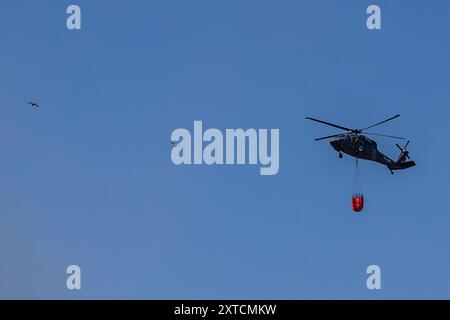 Ostrava, République tchèque. 14 août 2024. Un hélicoptère Sikorsky UH-60A Black Hawk intervient dans un incendie dans un complexe industriel de la société Skaltop à Vitkovice, Ostrava, République tchèque, août 2024. 12 unités de pompiers et 22 pièces d'équipement interviennent. Crédit : Vladimir Prycek/CTK photo/Alamy Live News Banque D'Images