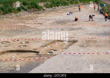 14 août 2024, Saxe-Anhalt, Belkau : des archéologues de l'Office d'État de Saxe-Anhalt pour la préservation des monuments et l'archéologie prélèvent des échantillons de sol sur un site de fouilles. Là, les archéologues ont trouvé des traces d'une colonie dont les maisons auraient été là vers 5000 av. J.-C.. Les seaux blancs encastrés dans le sol montrent les endroits où se dressaient les poutres de ces maisons. Les échantillons de sol doivent maintenant être examinés. Les archéologues veulent les utiliser pour savoir si les colons de l'époque y gardaient du bétail. Les fouilles ont eu lieu à la veille du constructio Banque D'Images