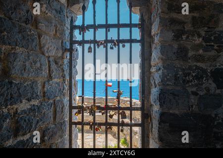 Porte avec clôture en fer et de nombreuses écluses avec la mer Méditerranée en arrière-plan. Église Saint-Pierre (Chiesa di San Pietro) à Porto Venere, Italie Banque D'Images