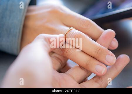 Un gros plan de deux mains, dont l'une porte une délicate bague dorée, alors qu'elles se touchent doucement. L'arrière-plan est légèrement flou, soulignant l'intimité de la maman Banque D'Images