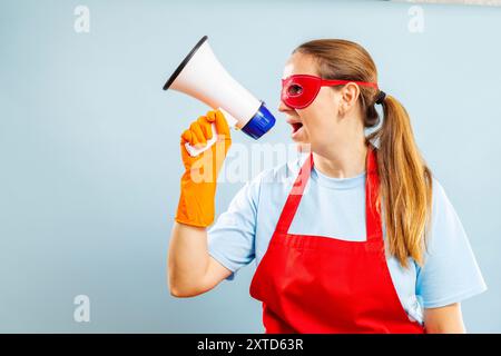 Femme criant à travers le mégaphone dans la tenue de nettoyage. Banque D'Images