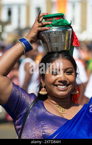 Femme dévote marchant à l'envers portant un pot de lait, connu sous le nom de "paal kudam", sur sa tête pendant le Tamil chariot Festival, un festival hindou. Ealing Banque D'Images