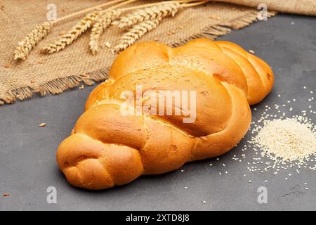 Pain tressé doré avec des graines de sésame sur une surface rustique, parfait pour les images de boulangerie et de stock alimentaire Banque D'Images