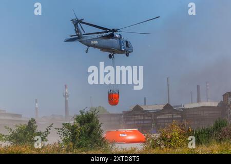 Ostrava, République tchèque. 14 août 2024. Un hélicoptère Sikorsky UH-60A Black Hawk intervient dans un incendie dans un complexe industriel de la société Skaltop à Vitkovice, Ostrava, République tchèque, août 2024. 12 unités de pompiers et 22 pièces d'équipement interviennent. Crédit : Petr Sznapka/CTK photo/Alamy Live News Banque D'Images