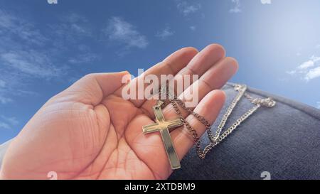 Une croix brune en bois reposant dans une paume ouverte, symbolisant la diffusion de l'amour de Jésus Christ à tous, une représentation puissante de la foi et de la Miss Banque D'Images