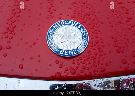 Emblème Mercedes Benz vintage avec des gouttes de pluie sur peinture rouge. ROYAUME-UNI. Banque D'Images