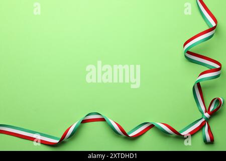 Ruban avec arc aux couleurs du drapeau hongrois sur fond vert, vue de dessus. Espace pour le texte Banque D'Images