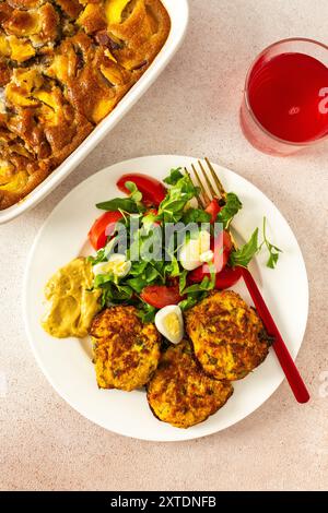 Savourez un petit déjeuner équilibré et appétissant composé de crêpes de courgettes avec laitue fraîche et tomates, accompagné de compote de cerises et d'un délicieux p de pêche Banque D'Images