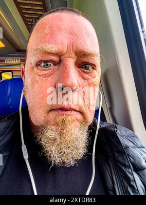 Autoportrait photographe avec casque mobile Autoportrait et Selfie du photographe et photojournaliste Guido Koppes lors de son trajet en train interurbain. Dordrecht, pays-Bas. MRYES Dordrecht Intercity Trein Zuid-Holland Nederland Copyright : xGuidoxKoppesxPhotox Banque D'Images