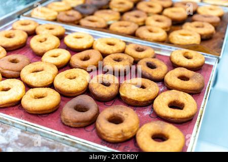 Production de beignets. Les beignets sont frits, glacés et disposés sur des étagères dans une boulangerie de beignets. Photo de haute qualité Banque D'Images