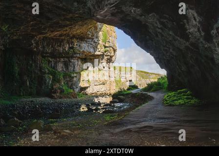 Découvrez le paysage captivant de Smoo Cave dans les Highlands, où les falaises de calcaire rencontrent des eaux sereines et une végétation luxuriante. Banque D'Images