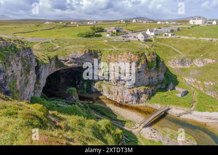 Découvrez le paysage captivant de Smoo Cave dans les Highlands, où les falaises de calcaire rencontrent des eaux sereines et une végétation luxuriante. Banque D'Images