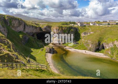 Découvrez le paysage captivant de Smoo Cave dans les Highlands, où les falaises de calcaire rencontrent des eaux sereines et une végétation luxuriante. Banque D'Images