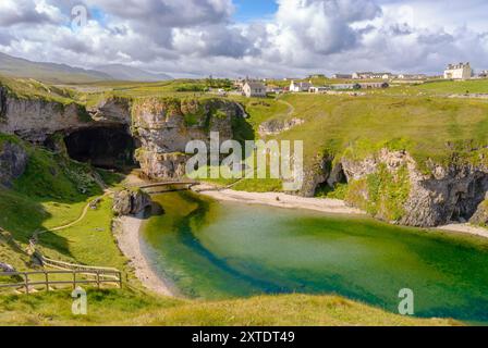 Découvrez le paysage captivant de Smoo Cave dans les Highlands, où les falaises de calcaire rencontrent des eaux sereines et une végétation luxuriante. Banque D'Images