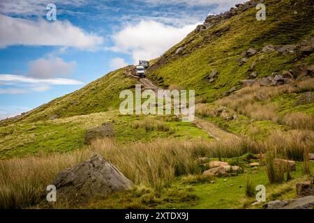Un petit groupe de véhicules 4x4 descend une colline abrupte et herbeuse dans les Yorkshire Dales, explorant la beauté naturelle du paysage. Banque D'Images