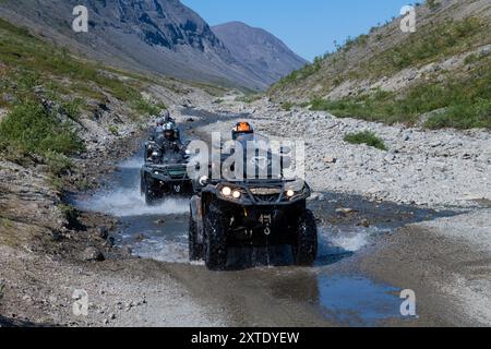 KIROVSK, RUSSIE - 27 JUILLET 2024 : touristes en VTT dans le lit de la rivière de montagne Kuniyok par un après-midi ensoleillé de juillet. Chaîne de montagnes Khibiny Banque D'Images