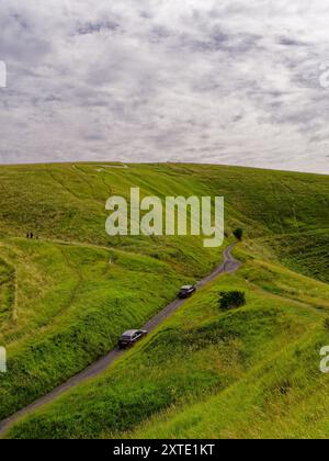 Cheval blanc d'Uffington avec des voitures sur la route et des touristes marchant sur une légère journée couverte à Uffington, Oxfordshire, Angleterre, Royaume-Uni Banque D'Images