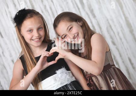 portrait de deux jolies filles preteen joyeuses dans des robes élégantes sur fond clair Banque D'Images