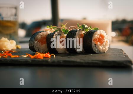 Une assiette de sushi avec un verre de bière sur la table. Les sushis sont disposés en rangée et ont une variété de garnitures, y compris des carottes et du persil. Scène Banque D'Images