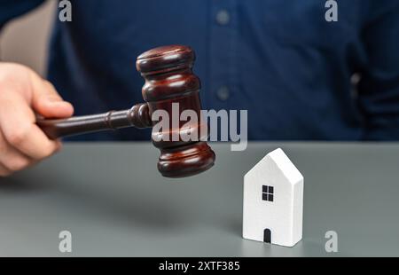 Figurine d'une maison et d'un homme avec un marteau de juges. Décisions des tribunaux de l'immobilier. Litige relatif à l'héritage de biens. Établissement de la propriété. Amnistie Banque D'Images